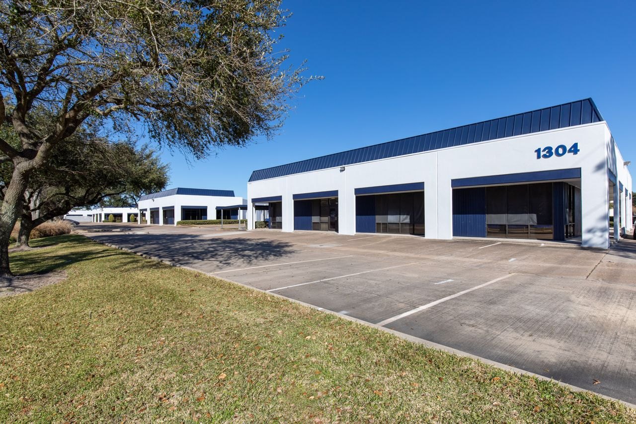 Flex building exterior — white single-story building with blue trim and large “1304” address numerals, 1304 Langham Creek Dr