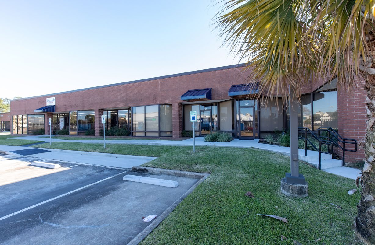 Flex building exterior — red-brick single-story building with blue awnings and glass storefronts, Westchase Business Park 3130 Rogerdale Rd